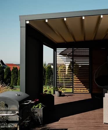 Eine moderne Außenterrasse in schlichtem Design mit Grill, Pflanzen und einem gemütlichen Sitzbereich, umgeben von üppigem Grün.