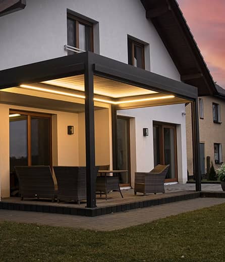 Moderne Terrasse mit eleganten Möbeln, von oben beleuchtet, an einem modernen Haus in der Abenddämmerung, das einen gemütlichen Lebensraum im Freien bietet.