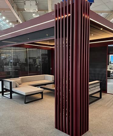 Modernes, offenes Sitzpavillon mit individuellen Designelementen wie vertikalen Holzlamellen und integrierter Beleuchtung in einer Ausstellungshalle.